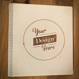 Könnte beinhalten: Ein helles Holzcover mit einem Kreisdesign, auf dem in dunkelbrauner Farbe "Your Design Here" steht.
