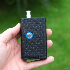 May include: A black leather case with a blue trim and a silver button. The case has a patterned design and a white mouthpiece.