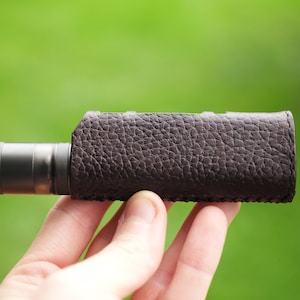 May include: A brown leather case for an electronic cigarette, with a metal mouthpiece.