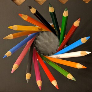 May include: A collection of colored pencils arranged in a radial pattern, with the tips of the pencils pointing outwards. The pencils are a variety of colors, including red, orange, yellow, green, blue, and white.