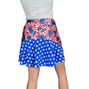 May include: A blue and red skirt with a pattern of American flags. The skirt is made of a stretchy fabric and has a flared silhouette.