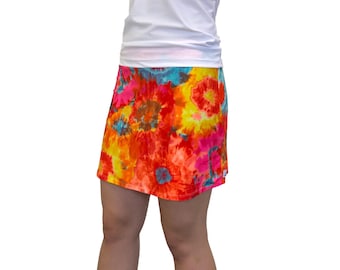 May include: A colorful tie-dye skirt with a floral pattern in shades of orange, yellow, pink, and blue. The skirt is made of a soft, stretchy fabric and has a comfortable fit.