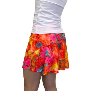 May include: A red, orange, yellow, pink, and blue floral print skirt with a white tank top.