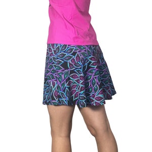 Op de afbeelding: Een zwarte rok met een kleurrijk bladmotief. De rok is gemaakt van een rekbaar materiaal en heeft een uitlopende pasvorm.