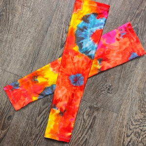May include: A pair of colorful tie-dye arm warmers with a bright orange, yellow, blue, and pink pattern.
