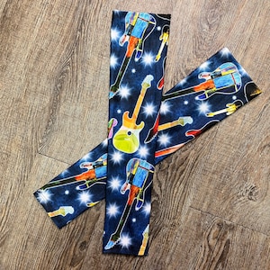 Peut inclure: Une paire de chauffe-bras bleus et noirs avec un imprimé de guitare coloré. L'imprimé de guitare est un mélange de bleus, de verts, de jaunes et d'oranges. Les chauffe-bras sont faits d'un tissu extensible et sont parfaits pour garder vos bras au chaud pendant les mois les plus froids.