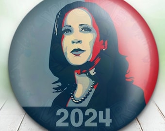 May include: A round button featuring a stylized portrait of a woman with the text "2024" at the bottom. The button has a red and gray background. The Woke Wear logo is in the upper left corner. The website "woke-wear.com" is in the upper right corner.