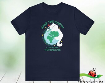 以下が含まれることがあります： 地球を抱きしめている白い猫が描かれたネイビーブルーのTシャツ。テキストには「Save the Earth」と「It's the only planet that has cats」と書かれています。
