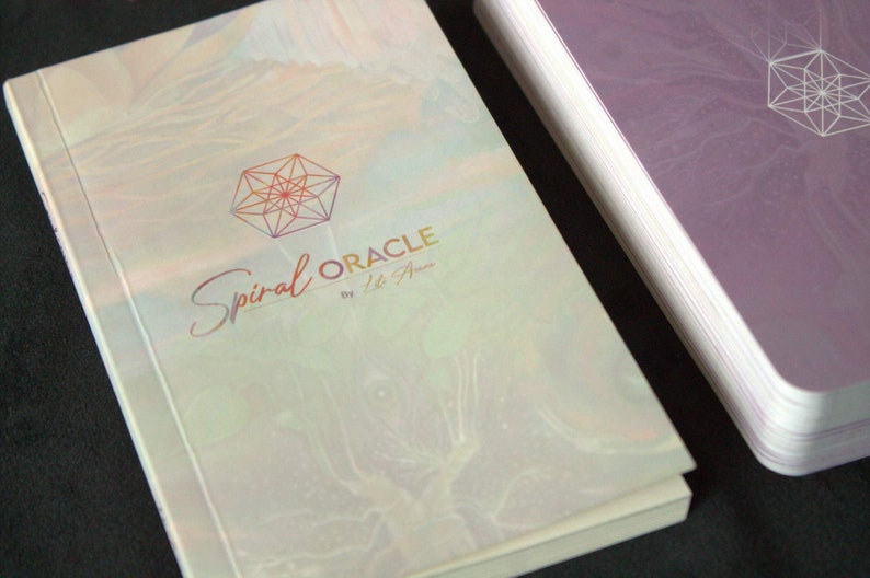 Może przedstawiać: Biała i tęczowa książka z geometrycznym wzorem i tekstem "Spiral Oracle by Lisa A."