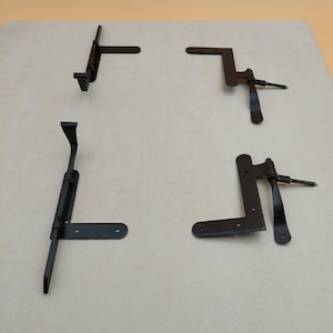 Puede incluir: Cuatro bisagras de metal negro con un diseño decorativo. Las bisagras están hechas de metal y tienen un acabado negro. Están diseñadas para ser utilizadas en puertas o portales.