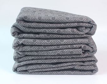 May include: A stack of six grey yoga mats with a black dot pattern. The mats are folded in half and stacked on top of each other.