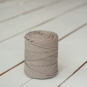 May include: A spool of thick, grey cotton rope. The rope is wound tightly and has a natural, rustic look.