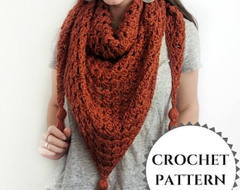 May include: A crochet shawl with a rust orange color and a crocheted tassel on each end. The shawl is draped around a person's neck and shoulders. The text "CROCHET PATTERN" is visible in the lower right corner of the image.