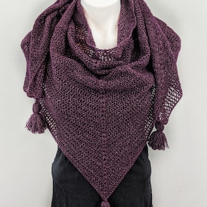 May include: A purple knitted shawl with a sparkly finish and three tassels. The shawl is draped over a mannequin.