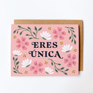 May include: A pink card with a floral design and the text "ERES ÚNICA" in black lettering.