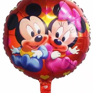 May include: A red, round foil balloon featuring Mickey Mouse and Minnie Mouse. Mickey is wearing blue and yellow, while Minnie is in pink. The balloon has a red stem and is decorated with hearts and other shapes.