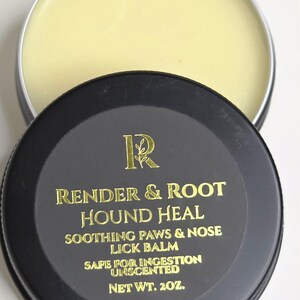 May include: A black and silver tin of Render & Root Hound Heal, a soothing lick balm for paws and noses. The lid features gold lettering with the product name and details, including "Safe for Ingestion" and "Unscented". The net weight is 57g.