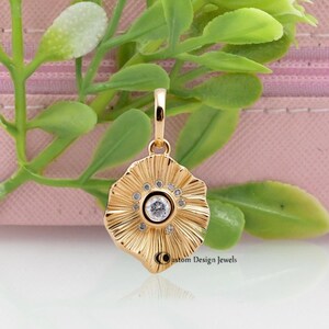May include: A gold pendant with a flower design and a clear crystal in the center. The pendant is surrounded by smaller crystals.