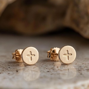 Può includere: Un paio di orecchini a perno dorati con un piccolo design a croce su ogni orecchino.