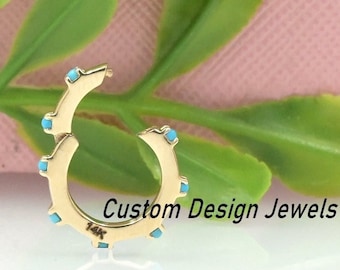 May include: A gold hoop earring with turquoise stones set around the edge. The earring is marked "14K" on the back.