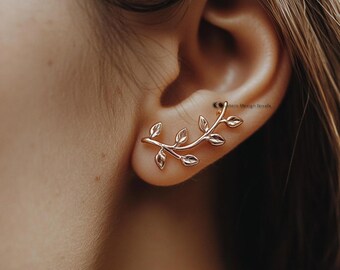 May include: Rose gold ear cuff featuring a delicate leaf design. The ear cuff curves along the ear, with small leaves branching out. The jewelry is a stylish accessory.