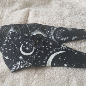 May include: Two black fabric face masks with a white crescent moon and star pattern.