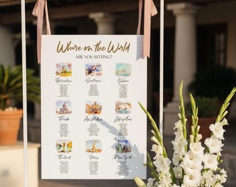 May include: A white rectangular wedding seating chart sign titled Where in the World ARE YOU SITTING? featuring nine watercolor illustrations of global cities including Barcelona, Santorini, Dubai, Florida, Amsterdam, Zakynthos, Thailand, Paris, and New York.