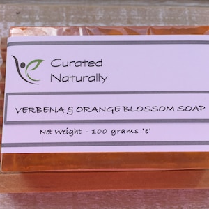 May include: A bar of orange and verbena scented soap with a label that reads "Curated Naturally" and "Verbena & Orange Blossom Soap" with a net weight of 100 grams.