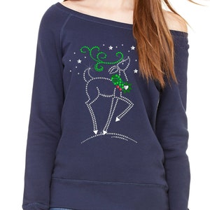 May include: A navy blue off-the-shoulder sweatshirt with a rhinestone reindeer design. The reindeer is holding a sprig of holly and is surrounded by silver glitter stars.