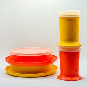 Może przedstawiać: Zestaw trzech plastikowych misek w kolorze żółtym i pomarańczowym z pokrywkami. Miski są ułożone jedna na drugiej. Pokrywki są w różnych kolorach.