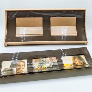 May include: A brown picture frame with three openings for photos. The frame is made of plastic and has a glossy finish. The frame is empty and ready to be filled with photos.