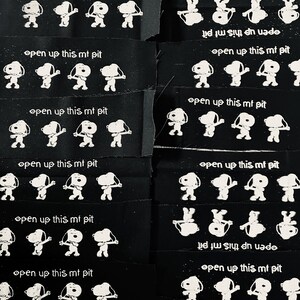 May include: A black fabric patch with a white outline of a cartoon dog and the text "open up this mf pit" repeated multiple times.
