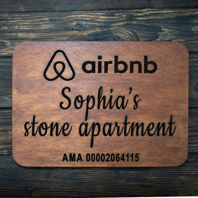 May include: A wooden sign with the Airbnb logo, the text "Sophia's stone apartment", and the code "AMA 00002064115".