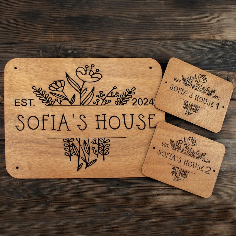 May include: Three wooden signs with a floral design and the text "EST. 2024 SOFIA'S HOUSE" on the largest sign. The smaller signs read "EST. 2024 SOFIA'S HOUSE 1." and "EST. 2024 SOFIA'S HOUSE 2."