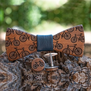 May include: A wooden bow tie with a blue fabric band and a bicycle pattern. The bow tie comes with a pair of matching cufflinks.