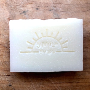 May include: A white bar of soap with a sun and the text "Simple Soaps" embossed on the front.