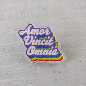 May include: A rainbow-colored sticker with the text "Amor Vincit Omnia" in white lettering.