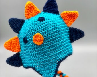 May include: A blue, orange, and navy blue crocheted hat with a long braided cord. The hat has a spiky design and a large orange circle on the front.