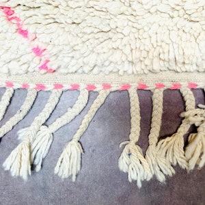 May include: White rug with a pink and white fringe. The rug has a pink stripe pattern.