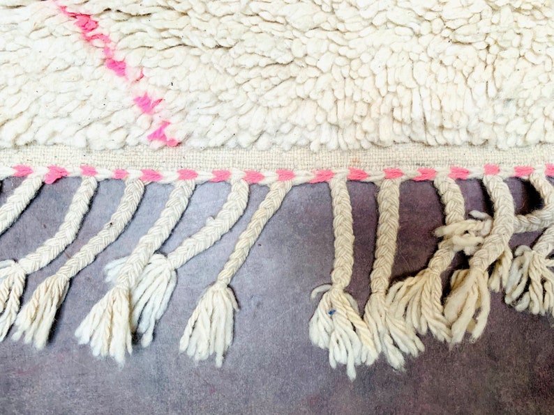 May include: White rug with a pink and white fringe. The rug has a pink stripe pattern.