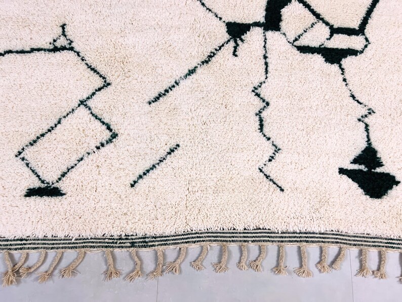 Detail shot of cream Beni Ourain rug displaying black abstract line work and authentic hand-knotted construction