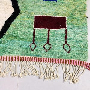 Green wool area rug featuring bold, colorful accents.