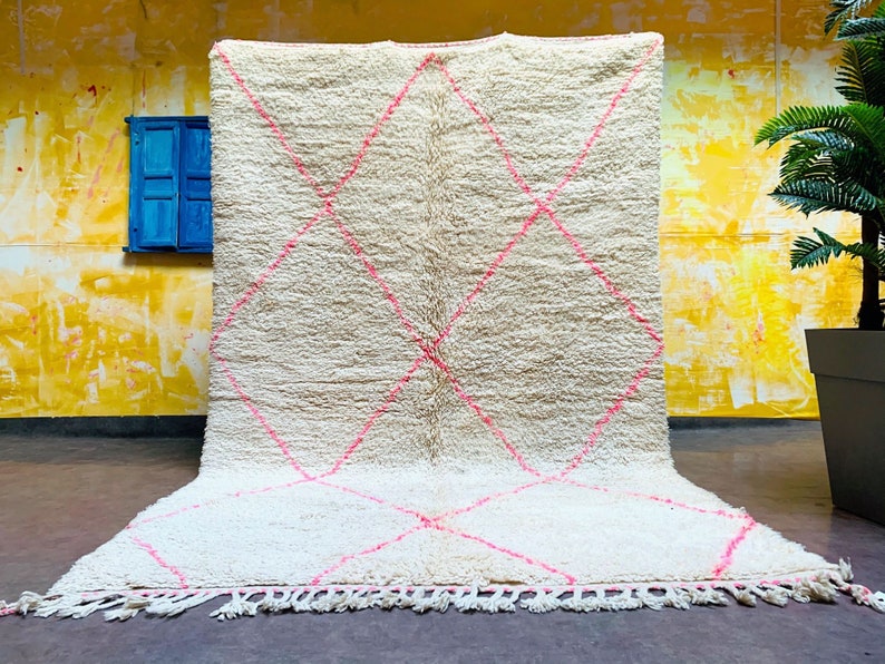 May include: A white shag rug with a pink diamond pattern. The rug has a fringe border.