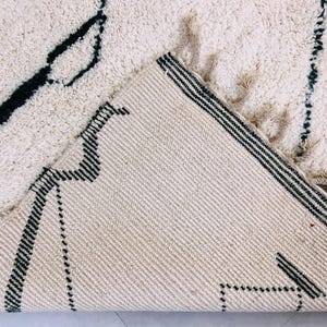 Side angle view of white Beni Ourain rug displaying black tribal patterns and authentic Berber craftsmanship