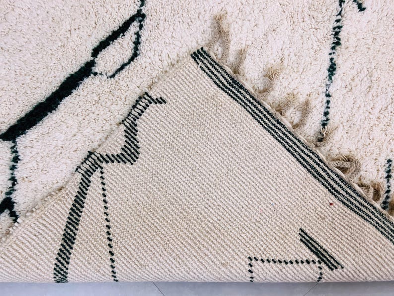 Side angle view of white Beni Ourain rug displaying black tribal patterns and authentic Berber craftsmanship