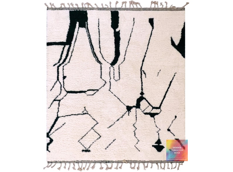 White Beni Ourain rug with black tribal line patterns and traditional fringe edges on neutral surface