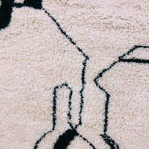 White Beni Ourain rug with black tribal symbols showing traditional Berber weaving patterns and natural wool pile