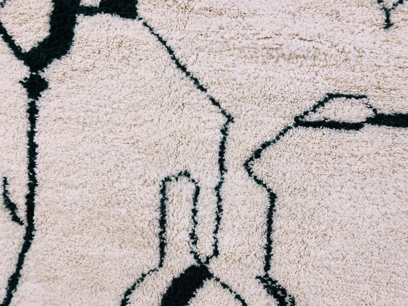 White Beni Ourain rug with black tribal symbols showing traditional Berber weaving patterns and natural wool pile