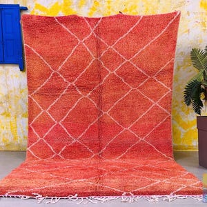 Handwoven Moroccan rug in warm red-orange tones with white diamonds.