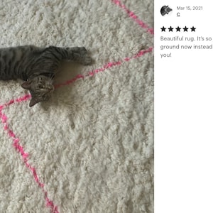 A 5 star review from a happy custom with a picture featuring a Pink and white Beni ourain rug with a cat laying on it